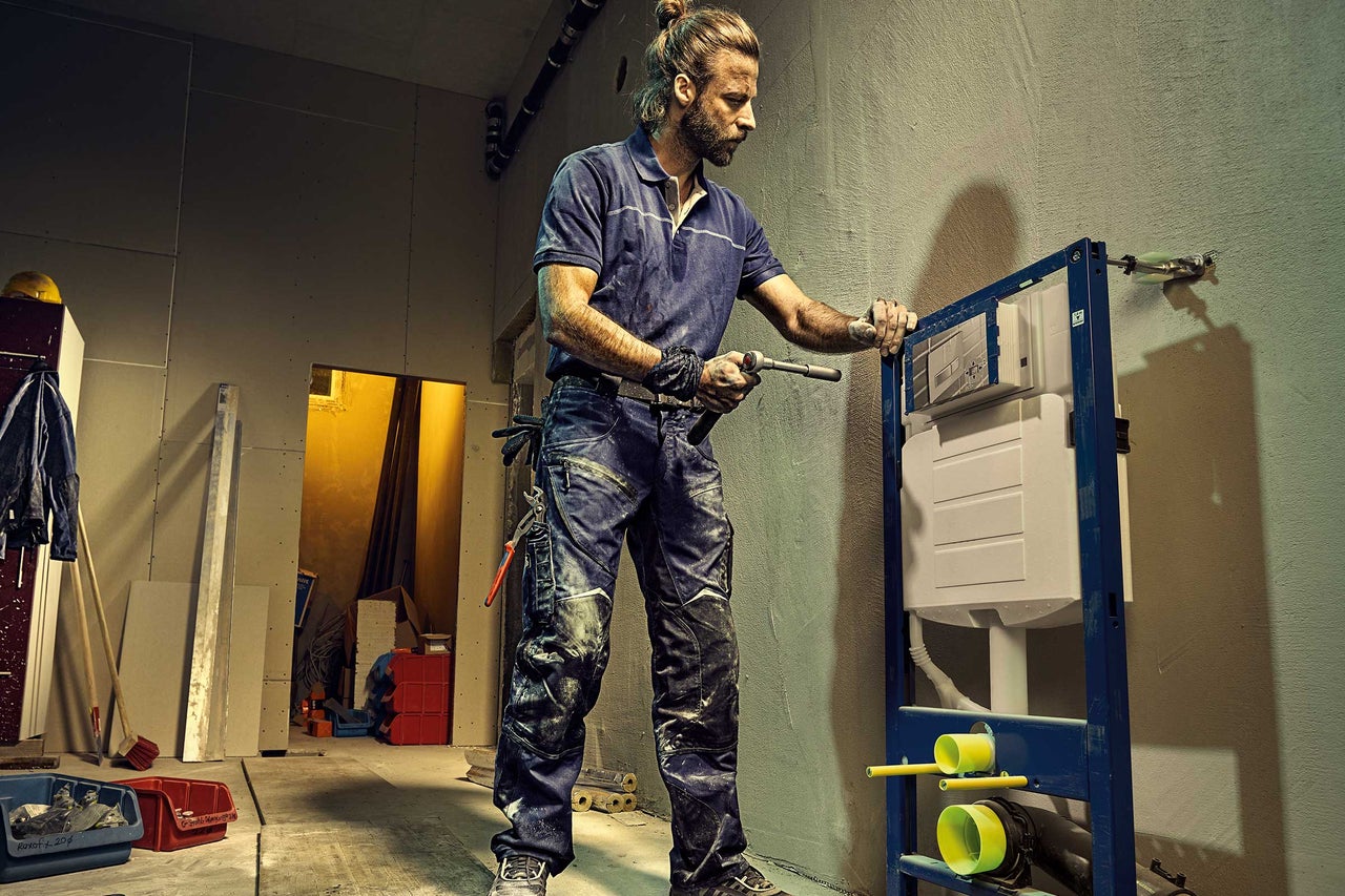 En rörmokare installerar en spolcistern i badrummet.