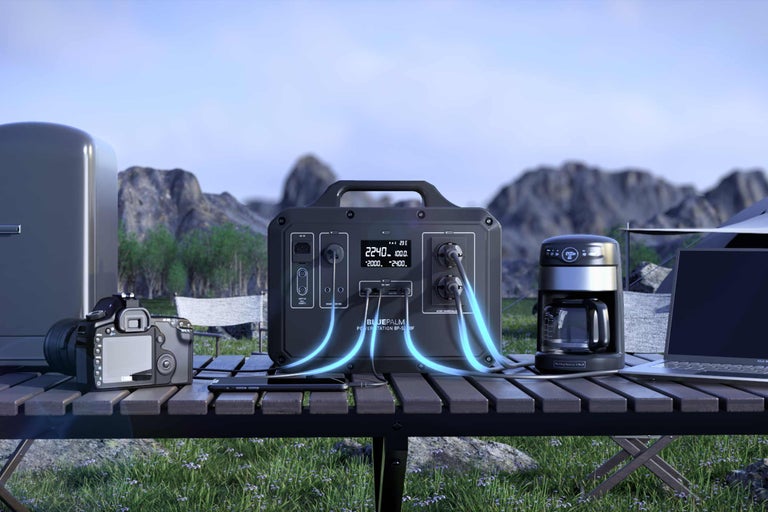 Scen med bärbar strömförsörjning, kamera, kaffebryggare, laptop och kylskåp utomhus