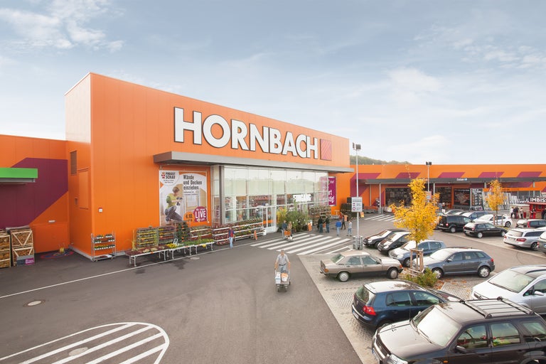 Utomhusvy av en Hornbach-byggmarknad med parkeringsplats och kunder