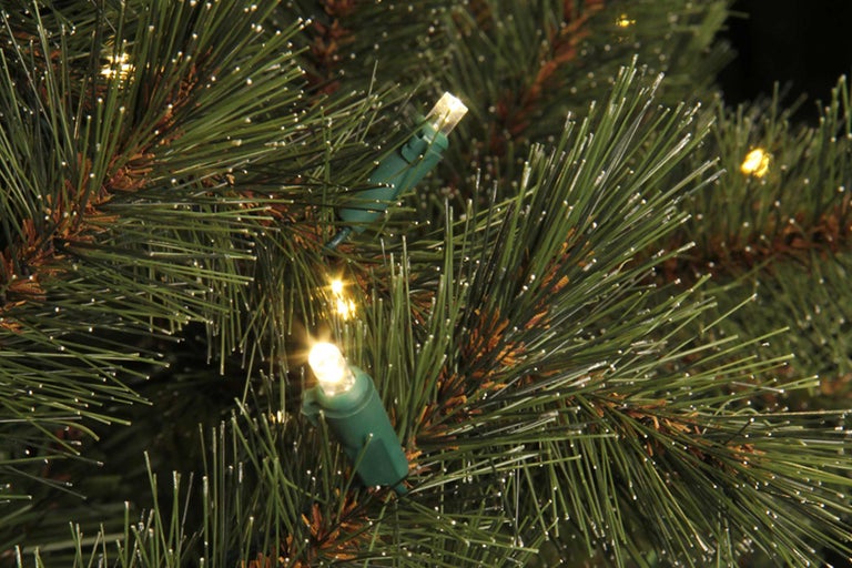 Närbild av en upplyst konstgjord julgran med gröna barr