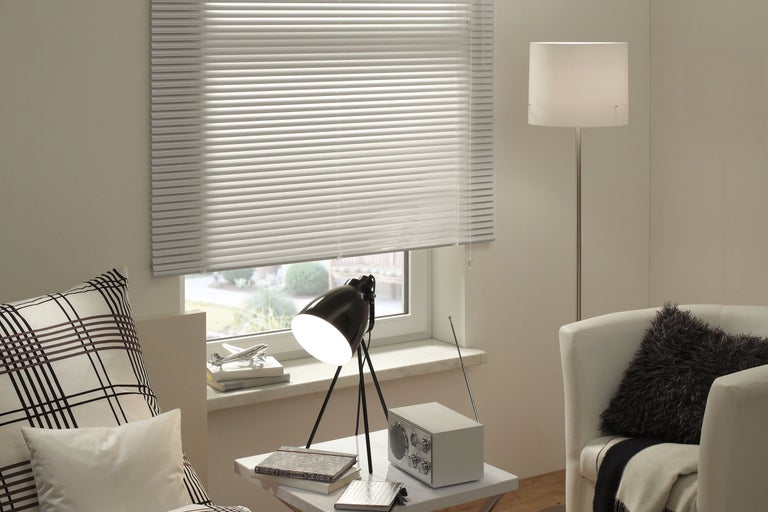 Vardagsrum med persienn, lampa, radio och fåtölj för en mysig atmosfär