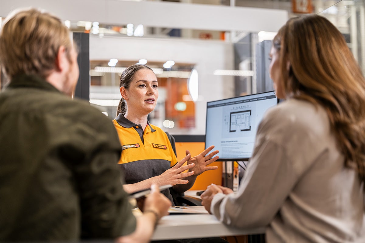 Hornbach medarbetare i rådgivningssamtal med två kunder framför en bildskärm som visar en planritning.