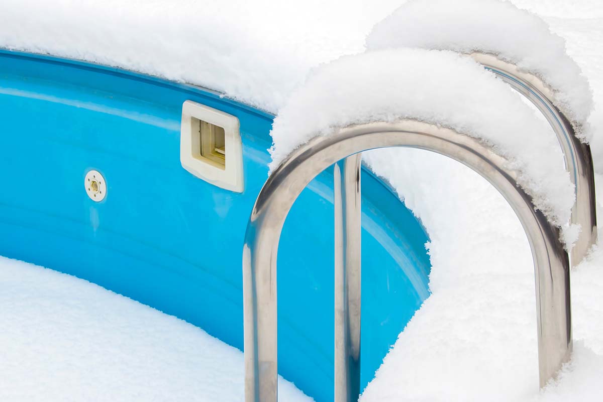 Blå pool med stege täckt av snö.