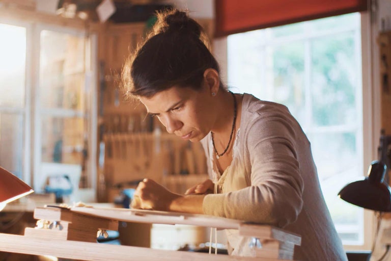 Kvinna som arbetar i en verkstad med träbearbetningsverktyg