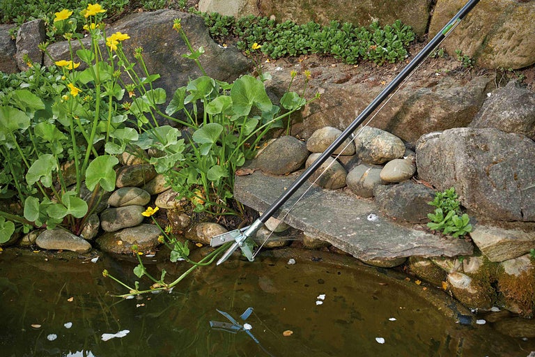 Damrengörare i drift vid en trädgårdsdamm