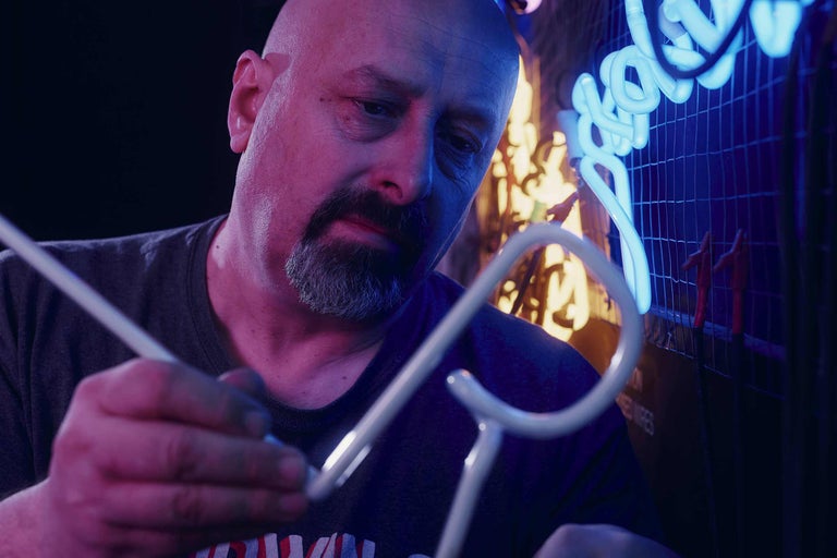 En man tillverkar en ljusreklam.