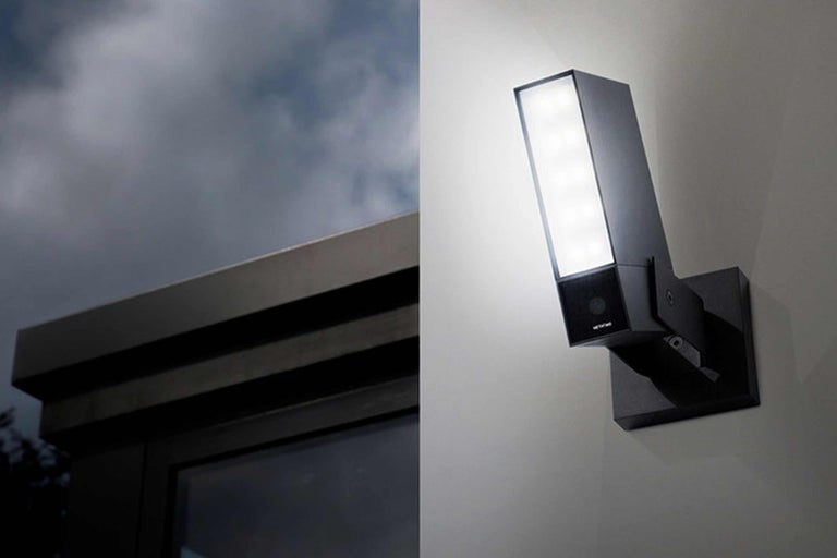 Mörk yttervägglampa med integrerad kamera monterad på en vägg