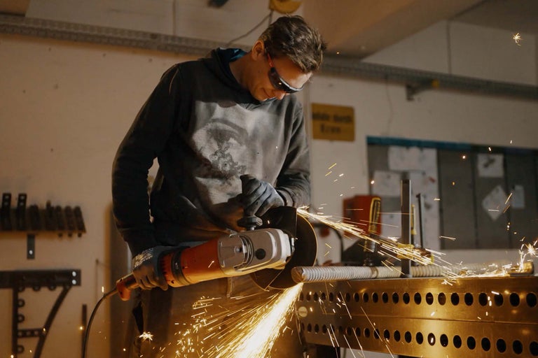 Man slipar metall med en vinkelslip, gnistor flyger