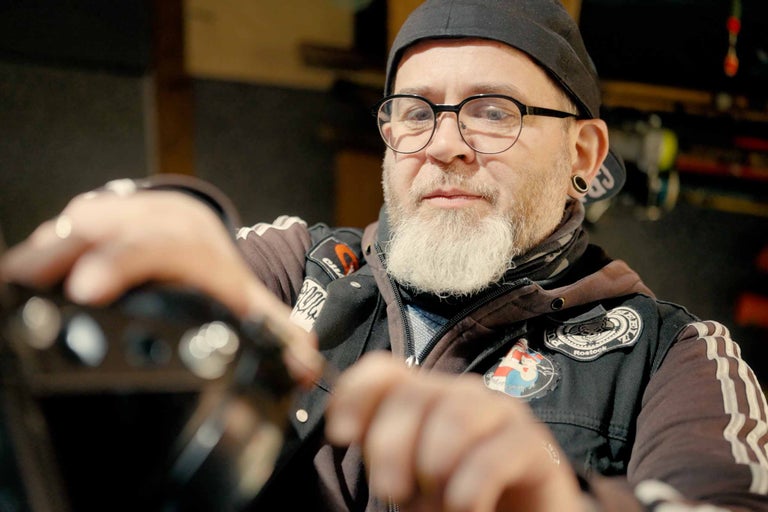 Man med skägg, glasögon och mössa monterar en produkt