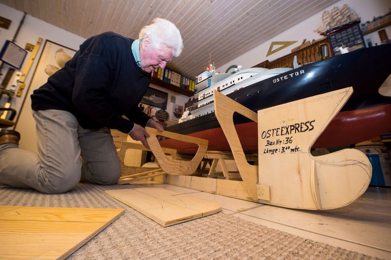 En man bygger en träfartygsmodell av 'Oste Express' i sitt hobbyrum