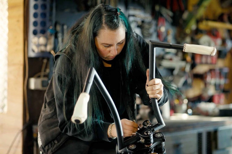 Kvinna monterar ett motorcykelstyre i en verkstad