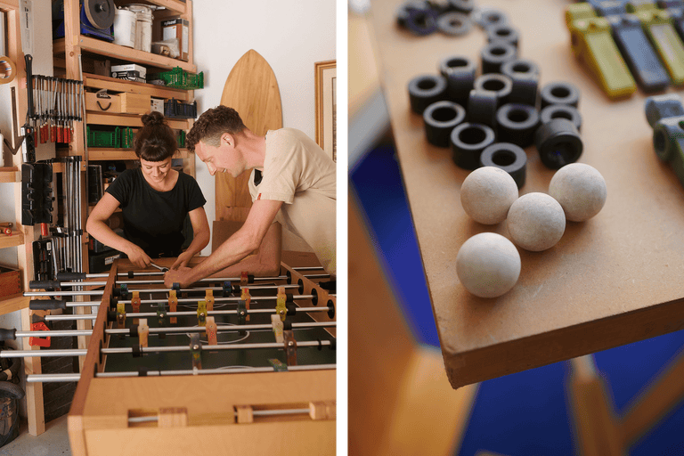 Två personer reparerar ett bordsfotbollsspel i ett hobbyrum; reservdelar finns tillgängliga.