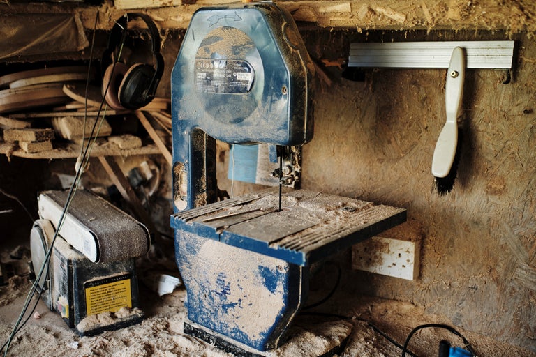 Verkstad med bandsåg, slipmaskin, hörselskydd och verktyg