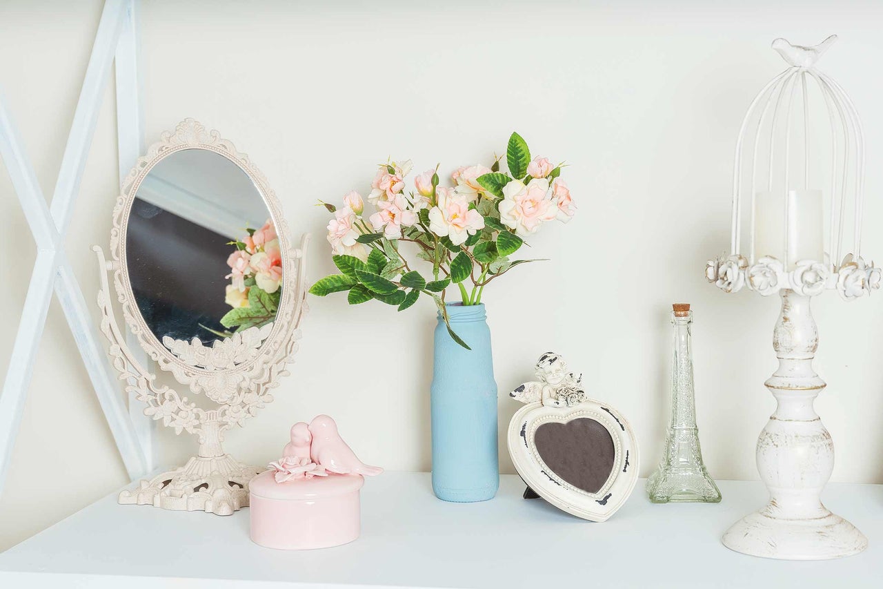 Dekorativt arrangemang med spegel, blommor i vas, smyckeskrin, fotoram och ljusstake