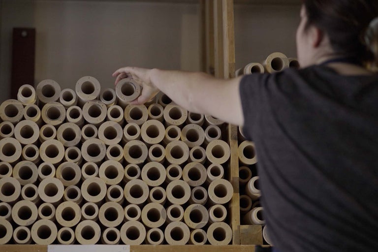 Bild av runda distanser i trä staplade i en hylla, där en person tar ut en distans.