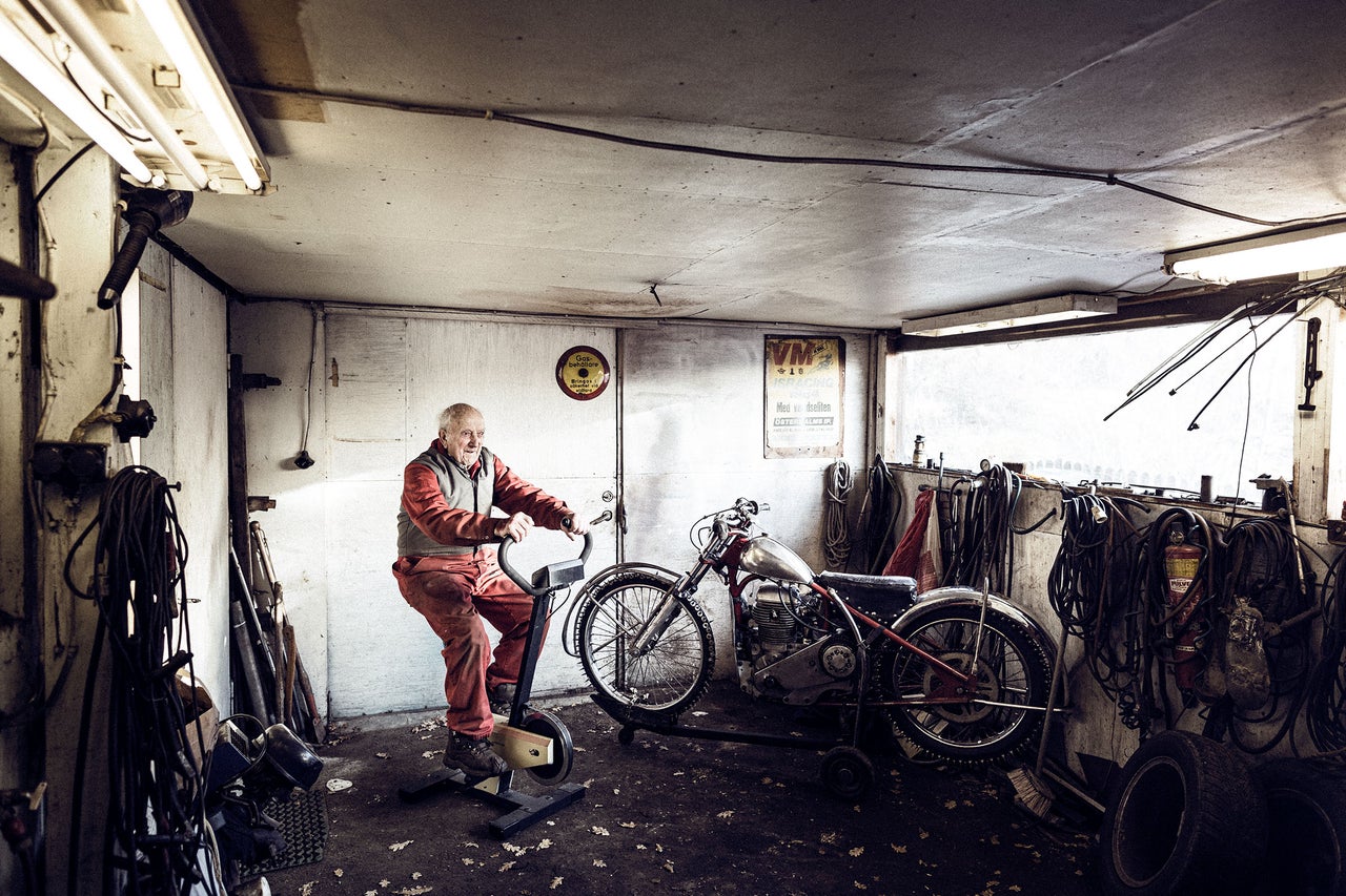 Verkstad med veteranmotorcykel och man på motionscykel