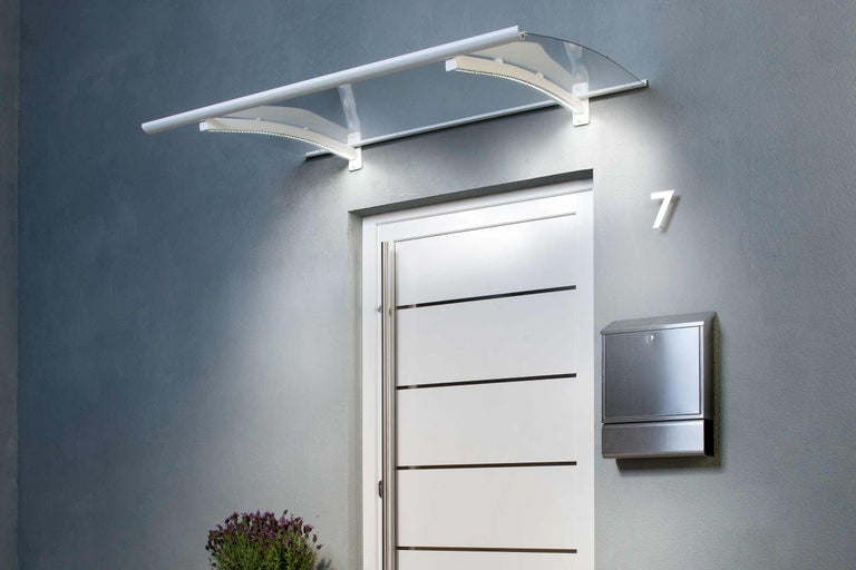 Tak med belysning ovanför en ytterdörr med brevlåda och husnummer.