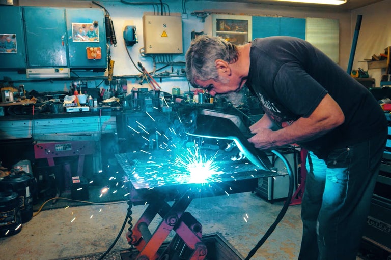 Man svetsar metall i en verkstad.