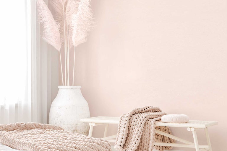 Ljus inredning med bänk, filt och vas med pampasgräs