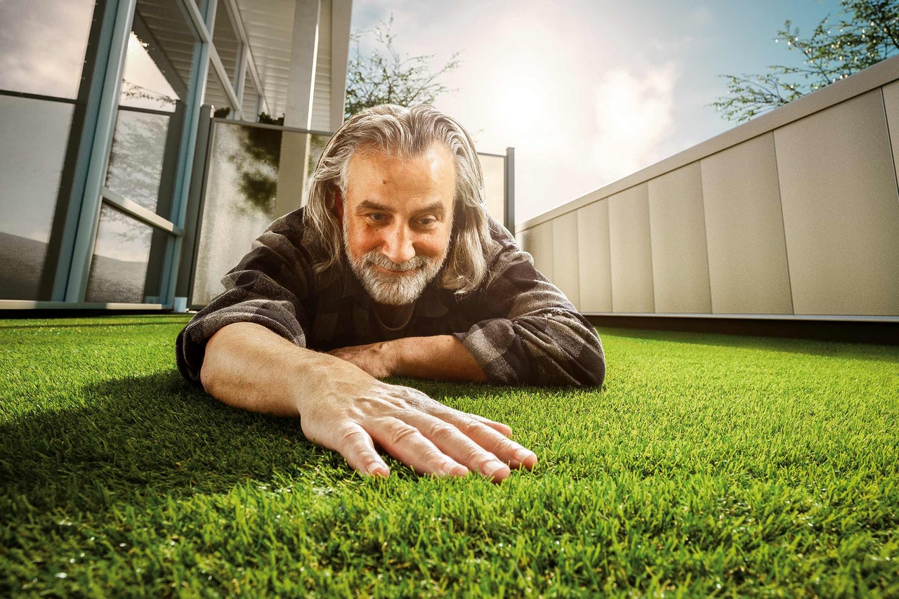 Man ligger på konstgräs och rör vid det med handen