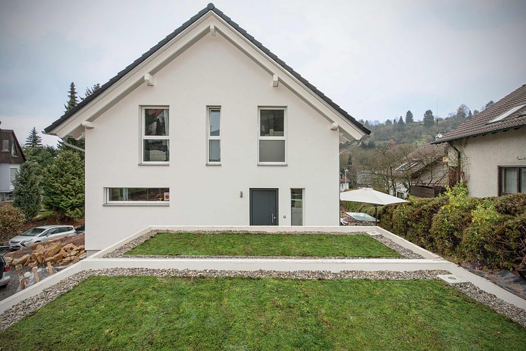 Modernt enfamiljshus med grönt platt tak och ljus fasad.