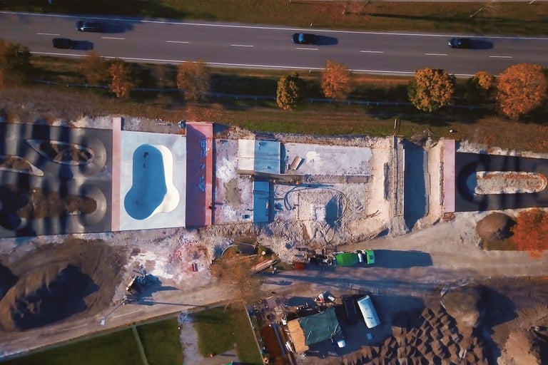 Flygfoto av en skatepark under uppbyggnad bredvid en motorväg