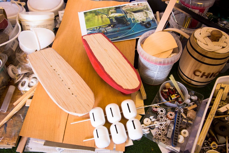 Verkstadsscen med verktyg, trädelar och en bild av ett fartyg