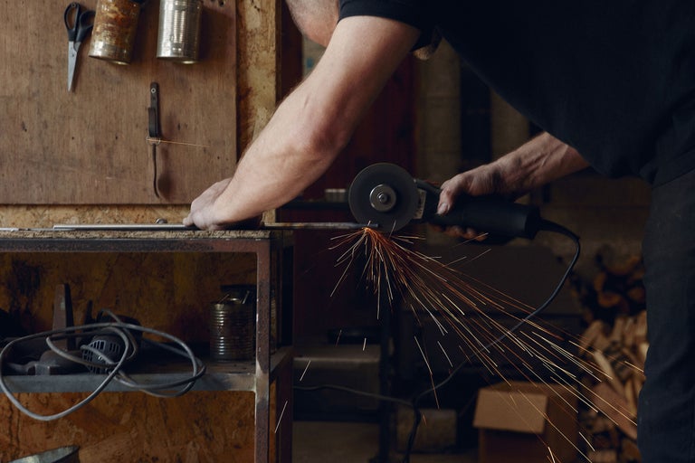 En man skär metall med en vinkelslip, och gnistor sprutar.