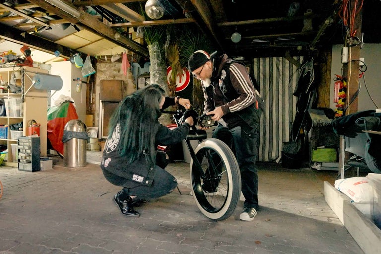 Två personer reparerar en cykel i ett garage.