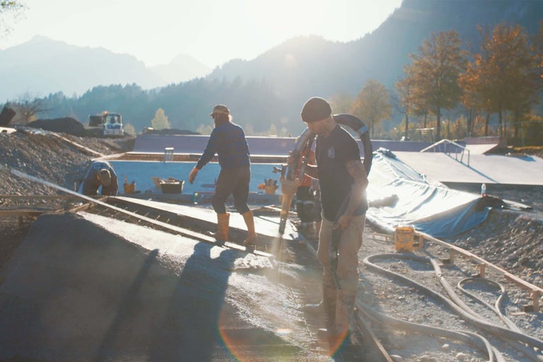 Byggnadsarbetare gjuter en skatepark med bergspanorama i bakgrunden