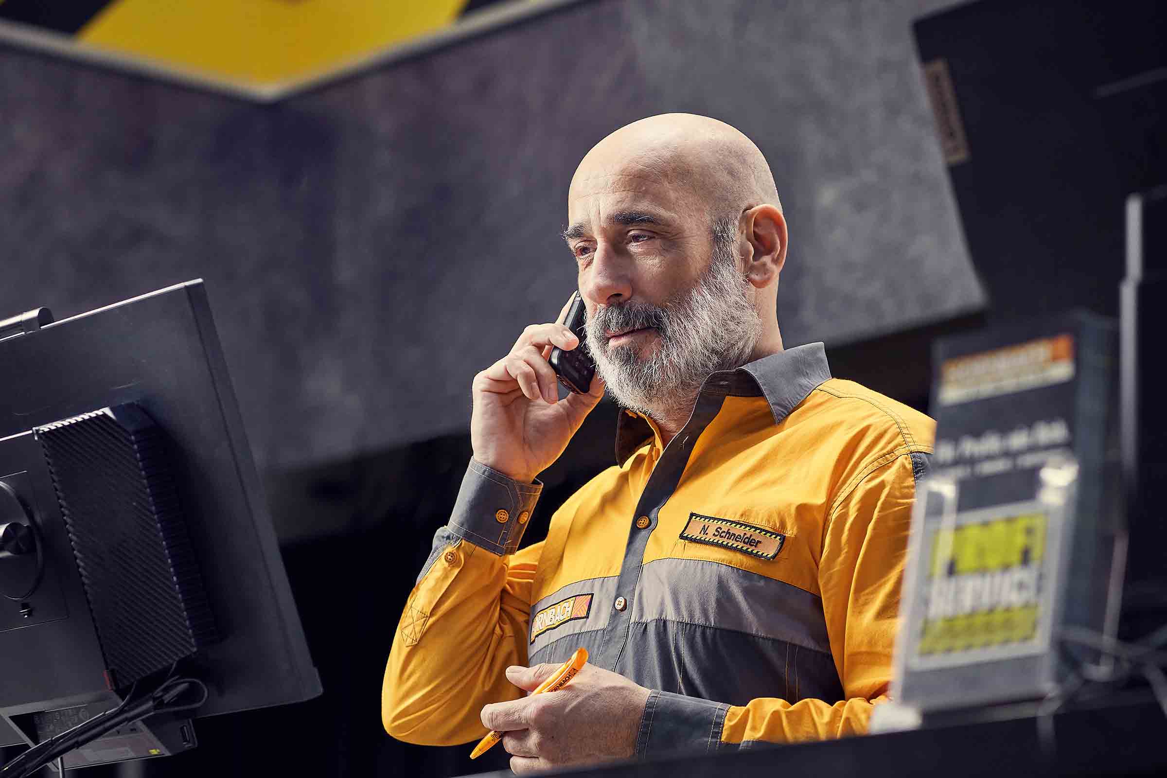 En Hornbach-anställd pratar i telefon och håller en penna i handen.