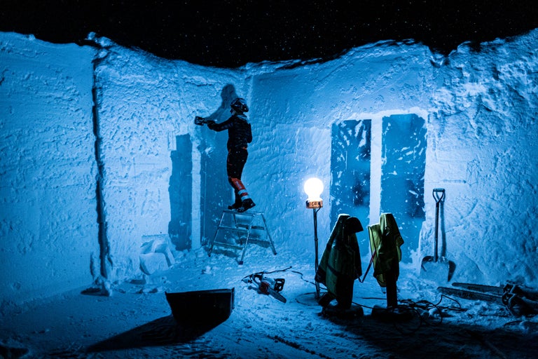 Byggande av snöskydd med verktyg och utrustning. Person står på en stege.