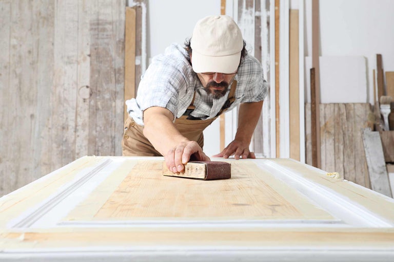 Man slipar trädörr med sandpapper