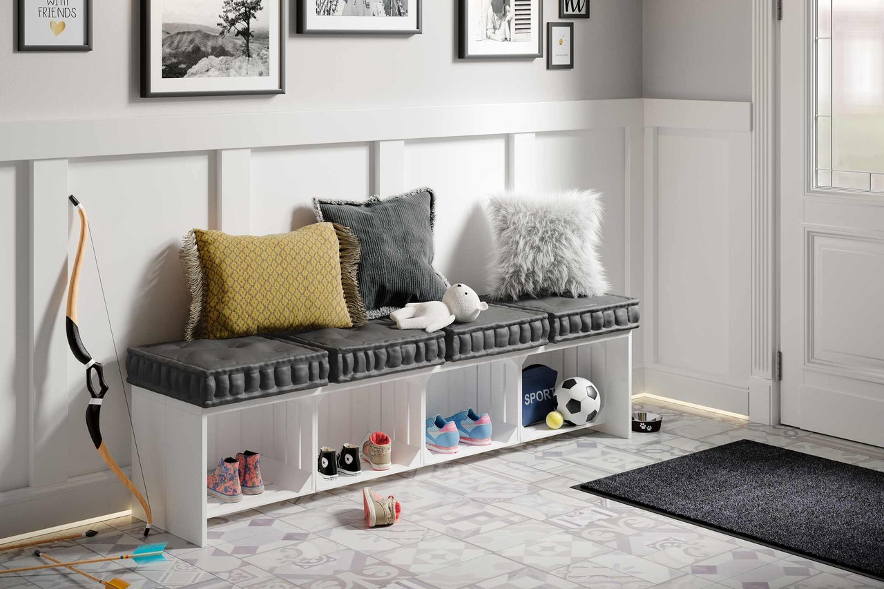 Hall med skoskåp, kuddar och dekorativa föremål på ett mönstrat golv