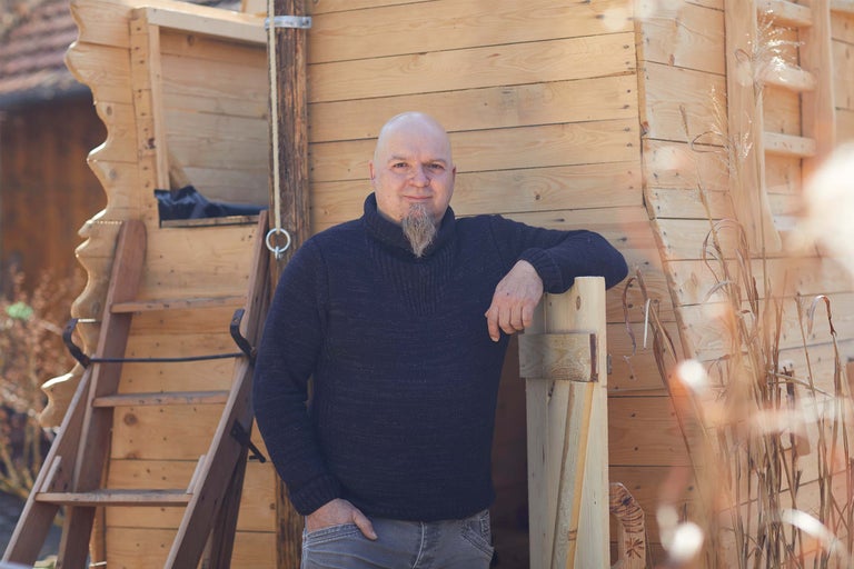 Man står framför ett trähus med stege.