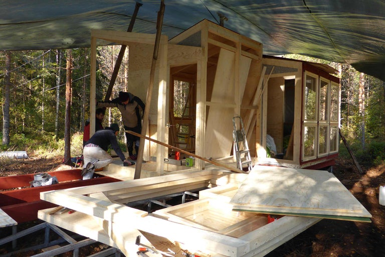 Byggnadsarbete på ett trähus utomhus med flera personer