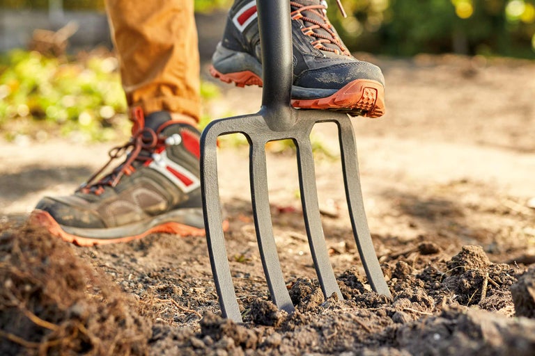 Person som trycker ner en grep i marken
