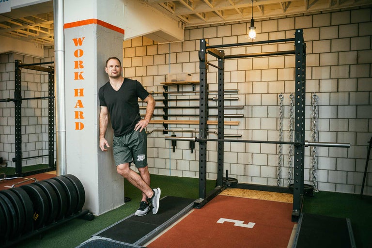 Gym med tyngdlyftningsområde och en man som lutar sig mot en vägg