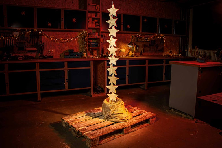 Verkstadsdekoration med trästjärnor på pall och ljusslinga i bakgrunden.