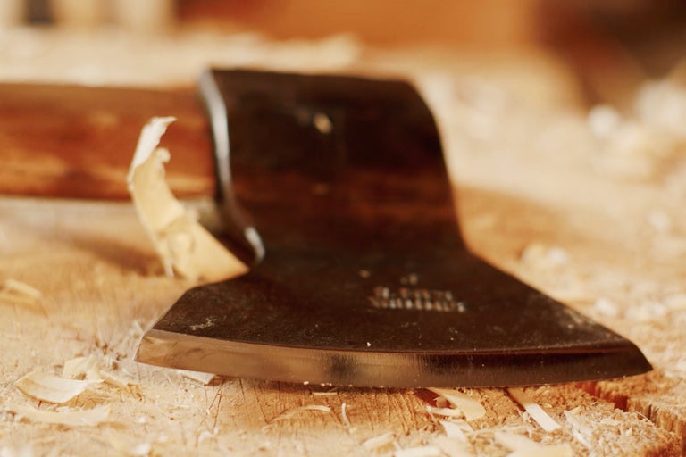 Närbild av en yxa på en träbit med träflisor