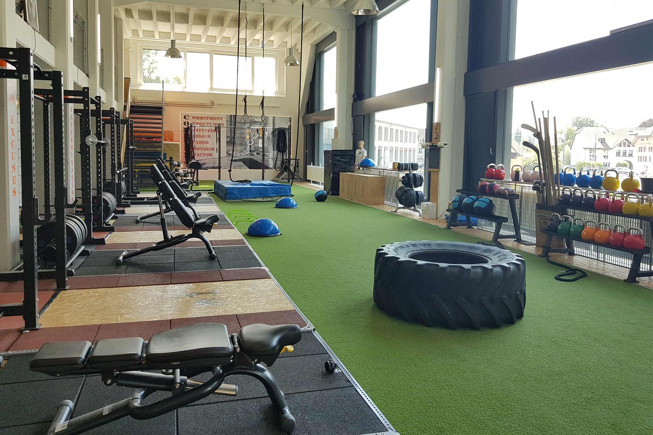 Ljust gym med vikter, träningsutrustning och ett stort däck