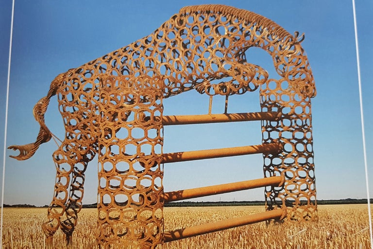 Hästskulptur av hästskor som hoppar över ett hinder, fält