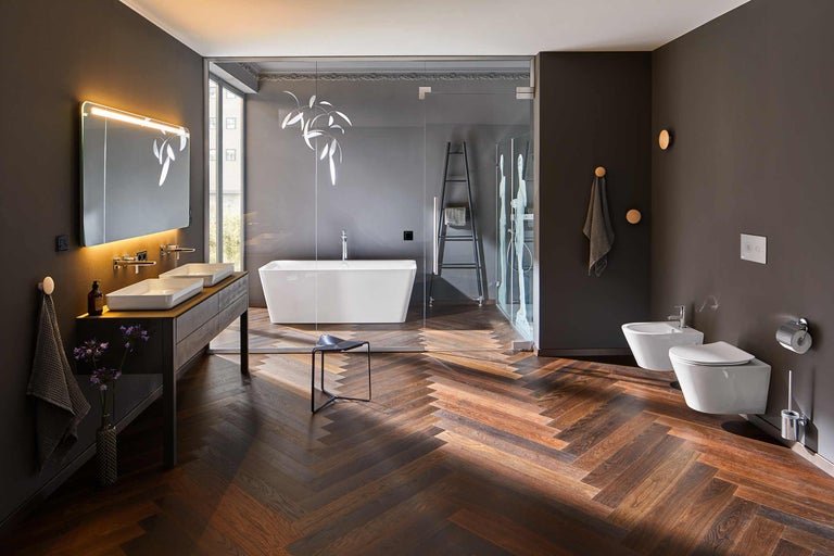 Badrum med badkar, dusch, handfat, toalett och bidé i mörka färger