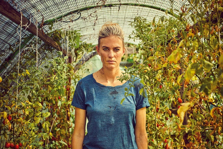 En kvinna står i ett växthus bland tomatplantor.