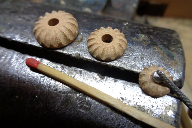 Tre dekorativa träpärlor med hål och en tändsticka