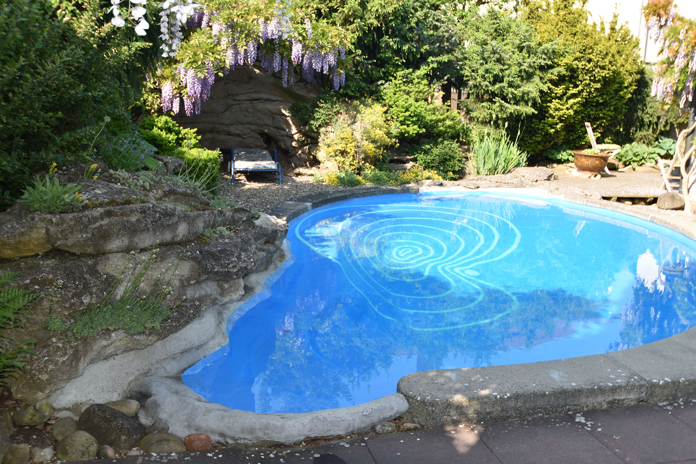 Pool i trädgården med blommande växter och stendekoration