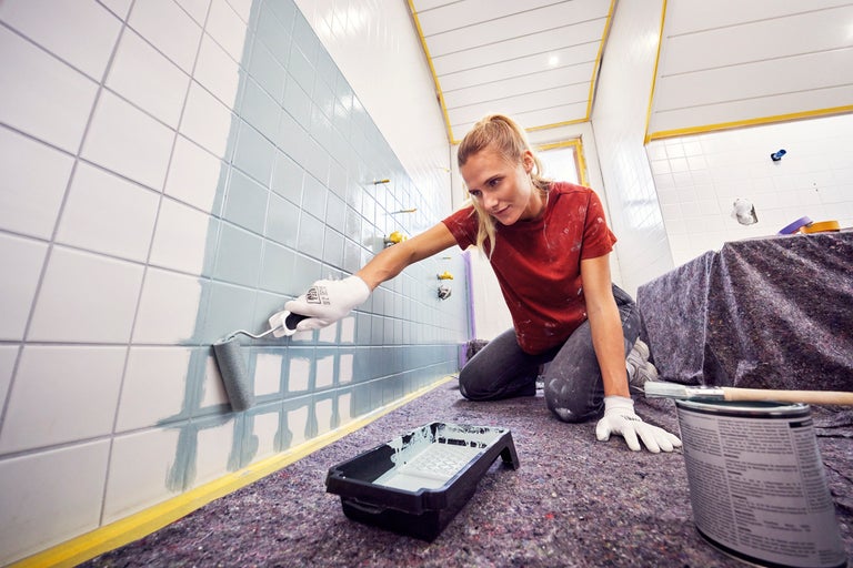 En person målar kakel med en färgroller.