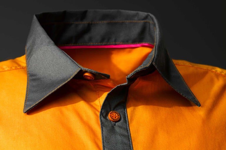 Närbild av en orange arbetsklädskjorta med grå krage och Hornbach-logotyp på knapparna.