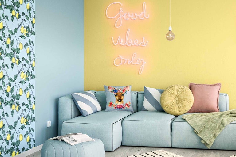 Ljust vardagsrum med turkos hörnsoffa, kuddar, neonbokstäver och citrontapet