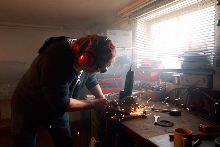 Man arbetar med vinkelslip i verkstad och bär skyddskläder.